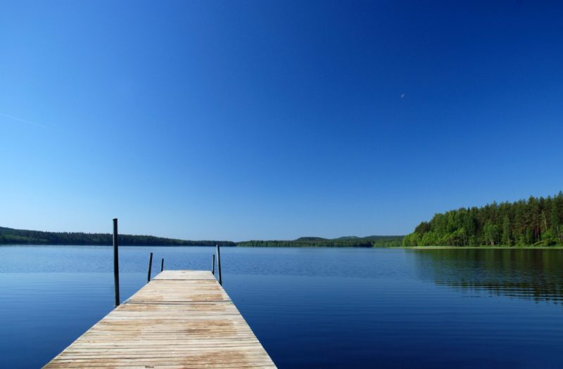 Kesäinen maisema, laituri ja sininen järvi ja taivas